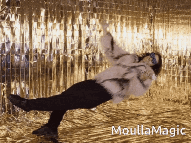 a woman in a fur coat is doing a trick in front of a gold wall with the words moullamagic on the bottom