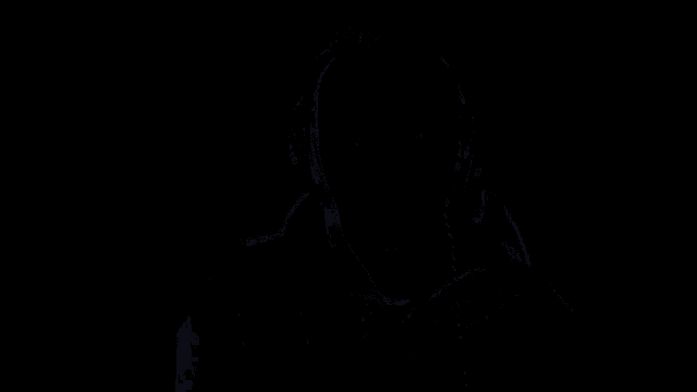 a man wearing headphones looks at the camera with a blue light behind him