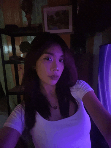 a woman in a white shirt is taking a selfie