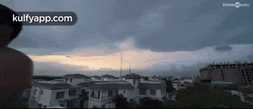 a man is standing in front of a cloudy sky over a residential area .