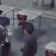 a group of people standing around tables and chairs in a classroom .