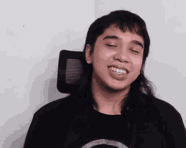 a man with long hair and a black shirt is smiling