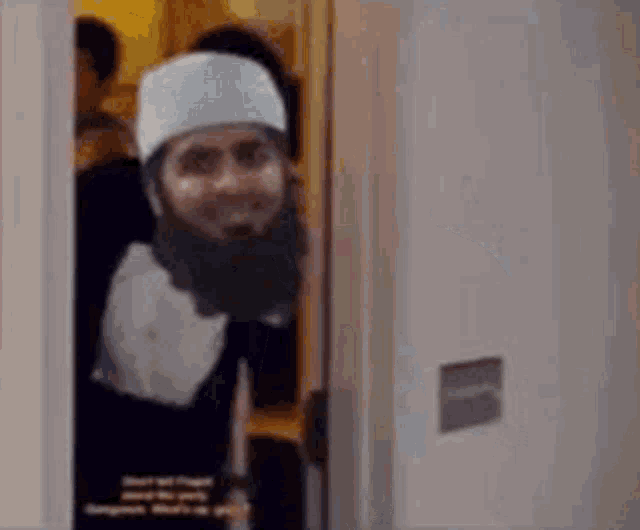 a man with a beard and hat is peeking out of a doorway .