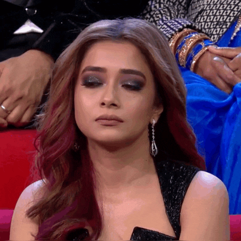 a woman with red hair and earrings is sitting on a red couch