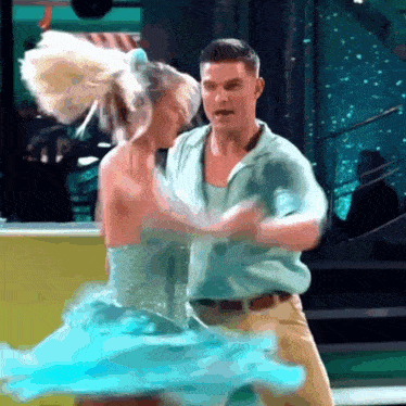 a man and a woman are dancing in a blue dress