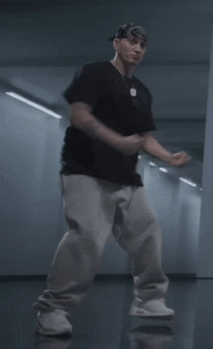 a man wearing a black shirt and grey sweatpants is dancing