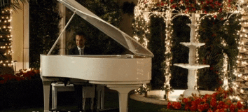 a man is playing a white piano in front of a fountain