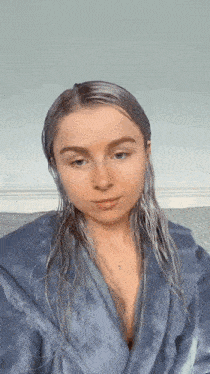 a woman with wet hair is wearing a blue robe .