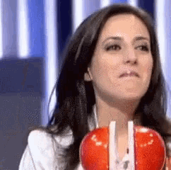a woman is holding a red apple with straws in it