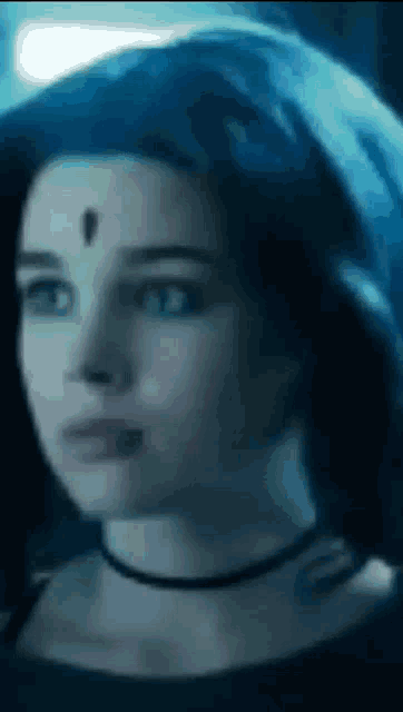 a close up of a woman 's face with a crescent moon on her forehead and a choker .