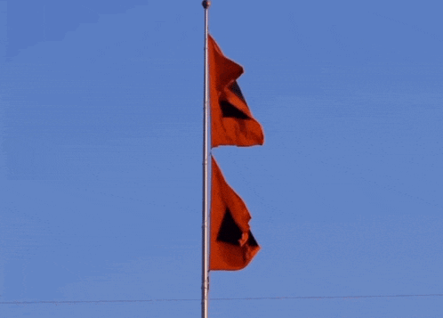 two red flags with black squares on them are flying in the wind