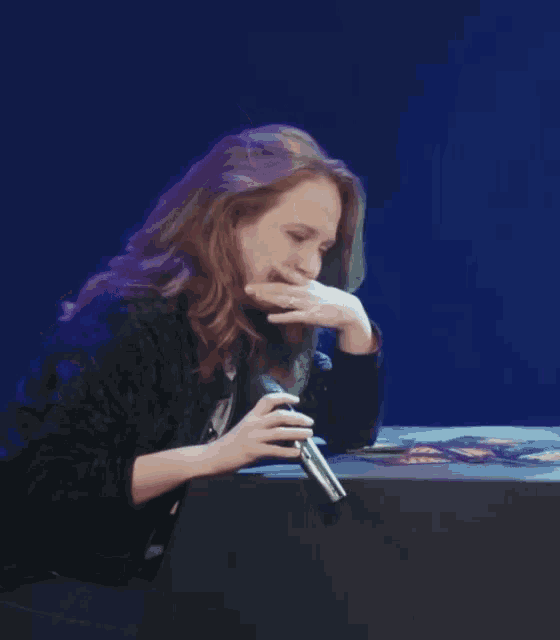 a woman is sitting at a table holding a microphone in her hand .