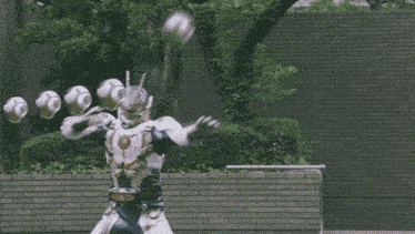 a man in a superhero costume is standing in front of a brick wall holding a fireball in his hand .