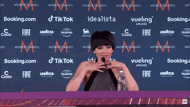 a woman speaking into a microphone with the words " i don t give a fuck " behind her