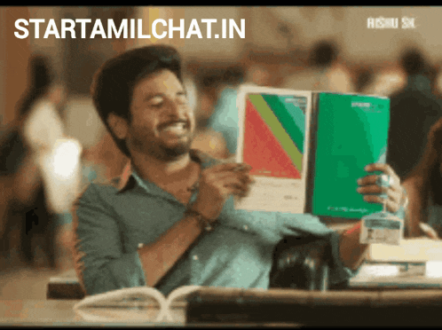 a man is smiling while holding a book and the website starttamilchat.in is above him