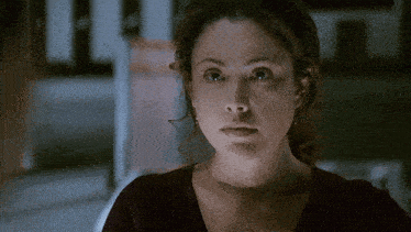 a close up of a woman 's face with a purple shirt on