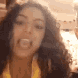 a woman with curly hair is making a funny face with her tongue out .