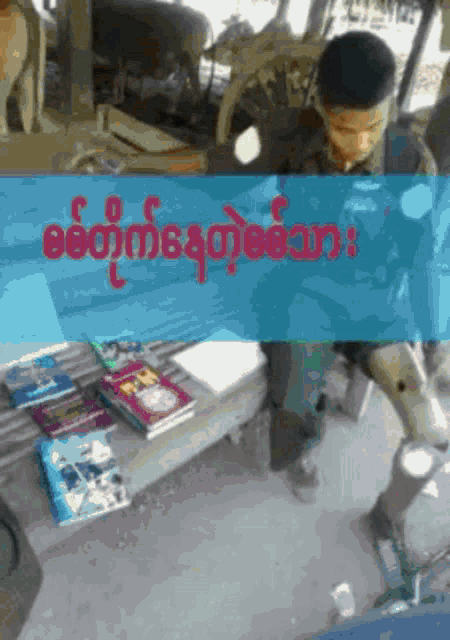 a man sitting on a bench with a bunch of books on it and the word myanmar in red