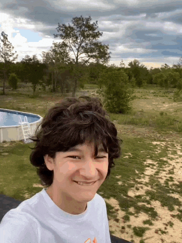 a young boy is taking a selfie in front of a swimming pool .
