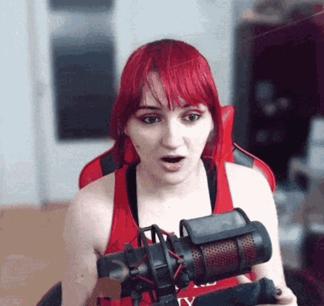a woman with red hair is sitting in front of a microphone and making a surprised face .