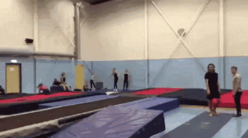a group of people are playing on trampolines in a gym