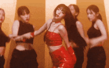 a woman in a red top and red pants is dancing in front of a group of women .