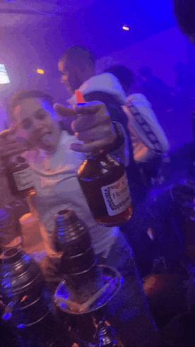 a man holding a bottle of hennessy in a club