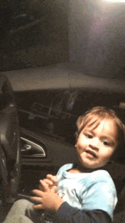 a little boy in a blue shirt sitting in a car