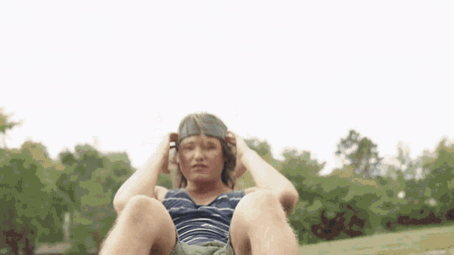 a man wearing a headband is doing sit ups outside