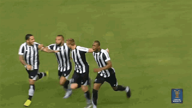 a group of soccer players in black and white striped jerseys are running on a field
