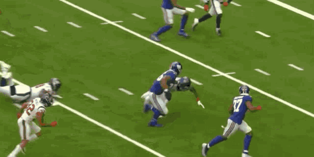 a football player is running with the ball on a field while another player watches .