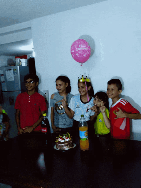 a group of children are celebrating a birthday with a pink balloon that says " feliz cumpleanos "