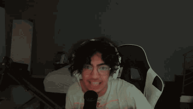 a man wearing glasses and a white shirt is making a funny face in front of a microphone