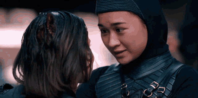 two women are looking at each other with one wearing a black hijab