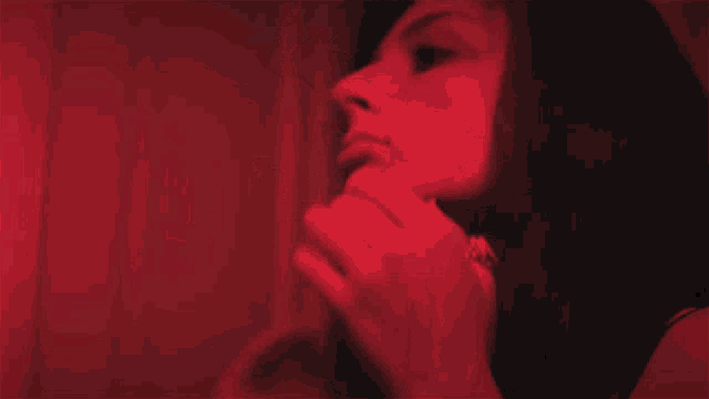 a woman covering her mouth with her hand in a red light
