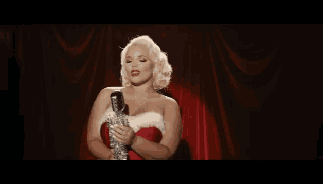 a woman singing into a microphone wearing a santa costume