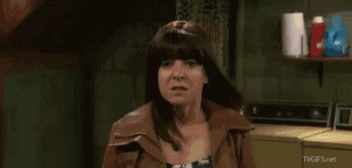 a woman in a brown jacket is standing in front of a laundry room .
