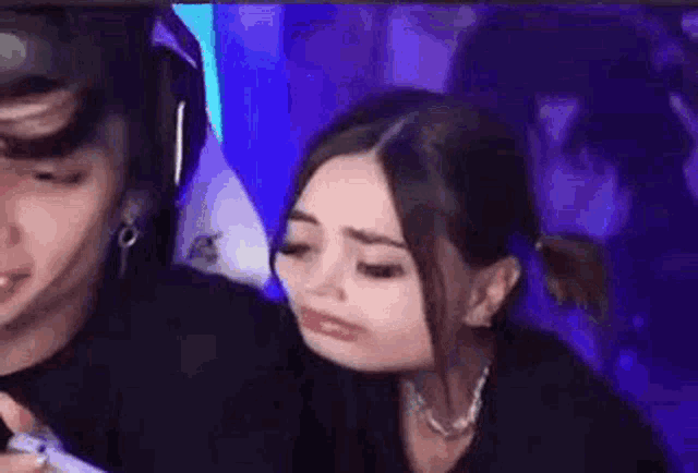 a woman is making a funny face while sitting next to a man in a gaming chair .