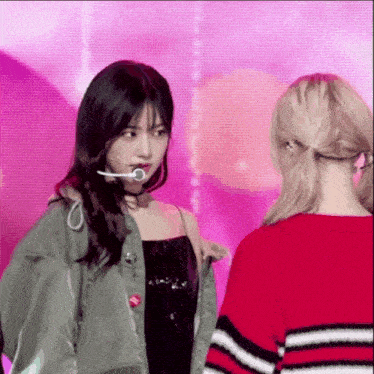 a woman in a green jacket stands next to another woman in a red striped sweater