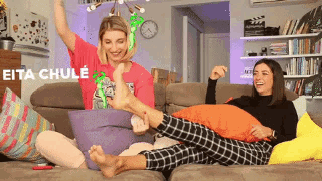 two women are sitting on a couch and one of them is wearing a shirt that says eita chule on it