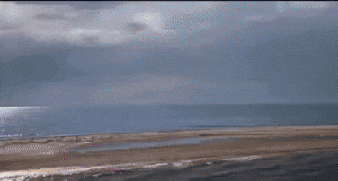 a blue ball is flying through a cloudy sky .