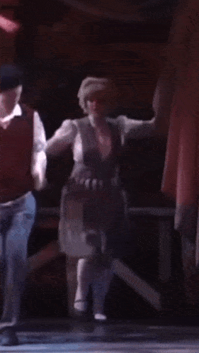 a man and woman are dancing on a stage in a dark room .