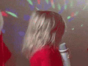a woman in a red dress is holding a microphone in a dark room .