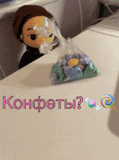 a bag of candy sits on a table next to a doll and the words konfety