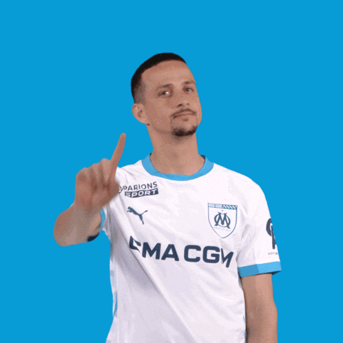 a man wearing a white maccg jersey points upwards