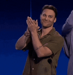 a man in a green shirt is clapping his hands in front of a blue background .