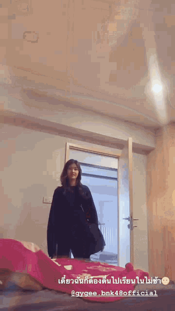 a woman in a black sweater is standing in front of a door in a room