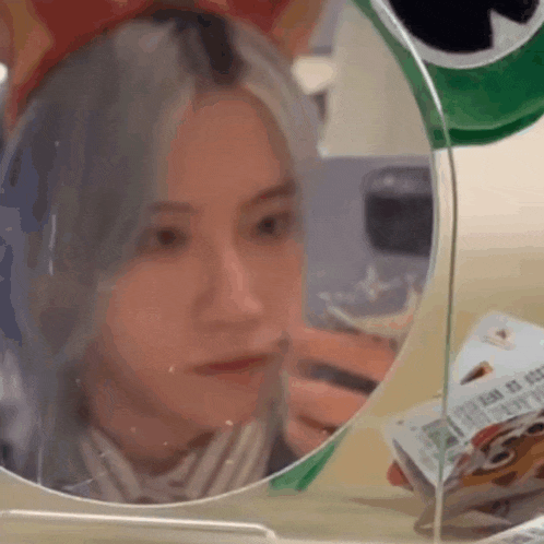 a woman is looking at herself in a mirror while wearing a cat ear headband .
