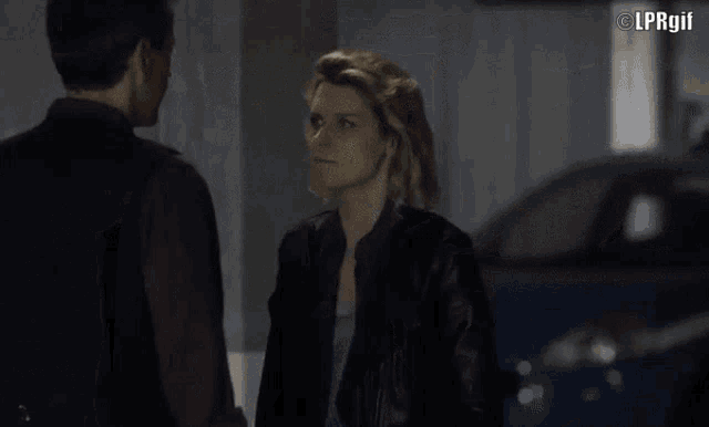 a man and a woman are standing next to each other in a dark room with lprgif in the corner