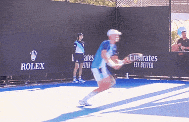 a man is playing tennis in front of a rolex ad